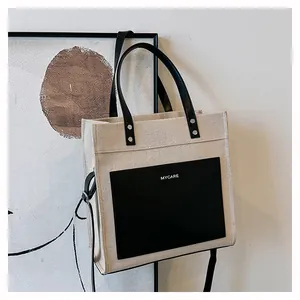 Close-up of beige canvas tote with black leather front pocket and MYCARE logo detail