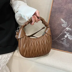 Detail of brown pleated cloud bag showing ruched handle and adjustable shoulder strap