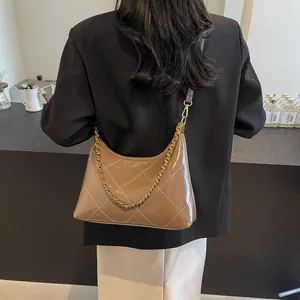 Brown quilted leather shoulder bag with gold chain worn by a model in a black blazer