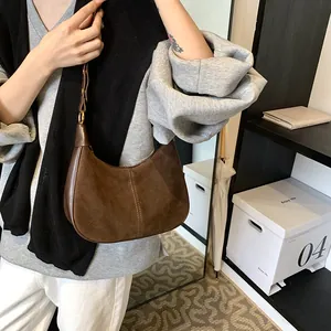 Détail du sac hobo en daim marron foncé avec ferrures en laiton et bandoulière cuir