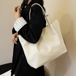 Close-up of a large white PU leather tote bag featuring slim shoulder straps for women