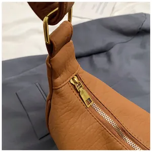 Détail du cuir marron texturé avec fermeture éclair dorée et anneau en D métallique