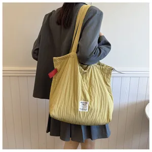 Detail of mustard yellow drawstring tote bag with vertical quilted texture and brand label