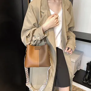 Detail of the brown bucket bag showing the contrast stitching and geometric woven strap