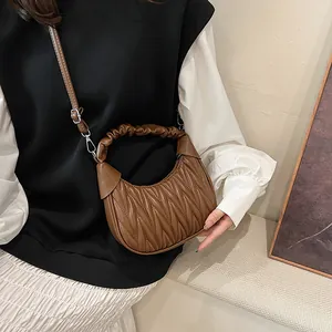 Detailed close-up of dark brown pleated crescent bag with luxury V-shaped texture