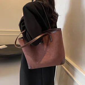 Detailed view of brown suede tote bag featuring contrasting leather straps on a model