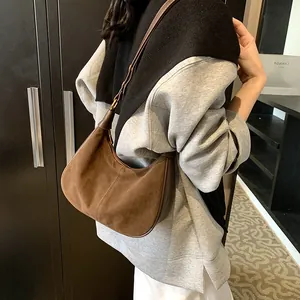 Détail du sac bandoulière en daim marron foncé avec finitions cuir et boucle en métal doré