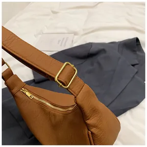 Détails de la texture du cuir caramel et de la fermeture éclair dorée sur le sac