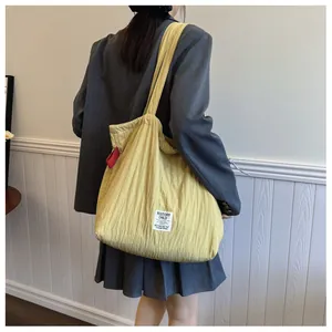Detail of a large yellow nylon tote bag featuring unique vertical pleated texture