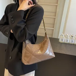 Detail of vintage brown glossy leather hobo bag with gold chain strap on woman