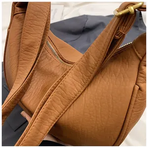 Détail d'un sac demi-lune marron chaud avec texture grainée et zip doré élégant