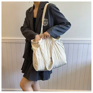 Detail of white quilted tote bag with vertical pleats and decorative woven label texture