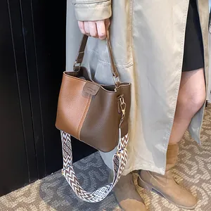 Detail of two-tone bucket bag with litchi grain leather and geometric wave shoulder strap