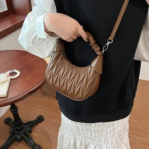 Close-up of brown pleated dumpling bag showing quality faux leather and handle texture