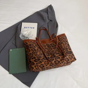 Flat lay of leopard print tote bag with brown leather handles and chic office props