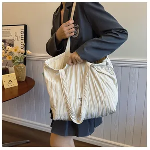 Detail of off-white pleated fabric tote bag with adjustable side drawstring and strap