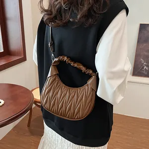 Close-up of brown pleated crescent bag with cloud handle and adjustable strap