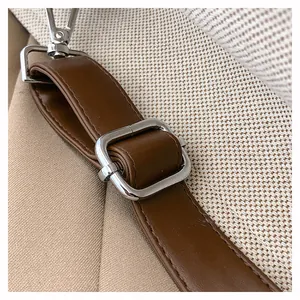 Close-up of brown leather strap with silver adjustable buckle on a canvas tote bag