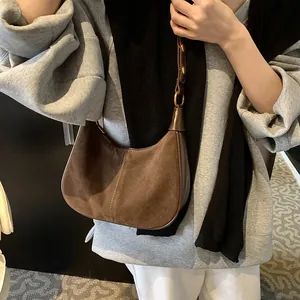 Gros plan sur un sac hobo en daim marron avec bandoulière réglable et anneau doré