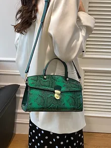 Schicke Handtasche mit grünem Schlangenmuster und Goldschnalle an einem Model