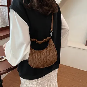 Detail of dark brown ruched dumpling bag with pleated texture and silver hardware