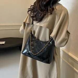 Detail of black quilted hobo bag with gold chain and vintage cracked leather texture