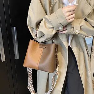 Detail of two-tone bucket bag with litchi texture and geometric patterned shoulder strap