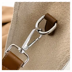 Detailed close-up of silver metal lobster clasp and D-ring on cream canvas tote bag