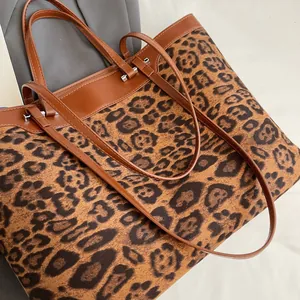 Detail of leopard print fabric texture and brown leather strap on a large tote bag