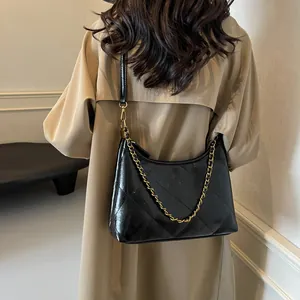 Close-up of quilted black crossbody bag with gold chain strap on a trench coat model