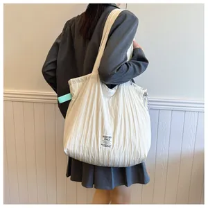 Macro view of white pleated nylon tote bag texture with logo label and drawstring detail