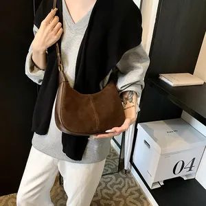 Détail du sac hobo en daim marron avec bandoulière en cuir porté par un mannequin