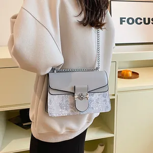 Detail of silver rose lock and snakeskin texture on grey crossbody chain bag