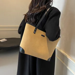 Side view of large khaki tote bag with black leather straps on model's shoulder