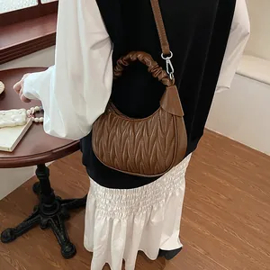 Close-up of a brown pleated crescent moon bag with V-quilted faux leather finish