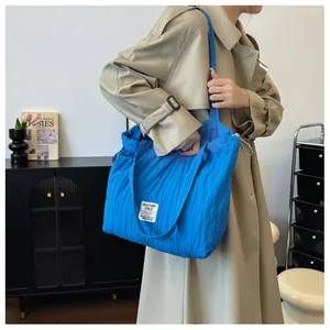 Detail of vibrant blue quilted nylon tote bag with drawstring and white label tag