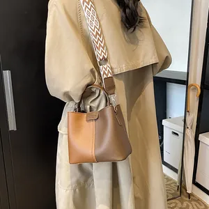 Detail of bicolored bucket bag with decorative patterned wide shoulder strap