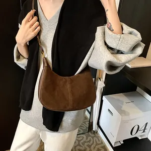 Détail macro du sac hobo en daim marron foncé avec couture centrale et bandoulière