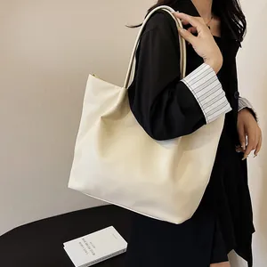 Side view of model wearing a large cream white leather tote bag with long straps