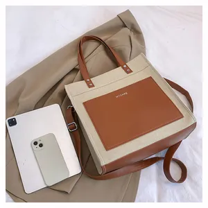 Detail of canvas tote bag showing MYCARE print with leather pocket and shoulder strap