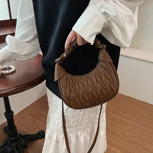 Close-up of brown quilted cloud bag featuring wave pattern and pleat handle details