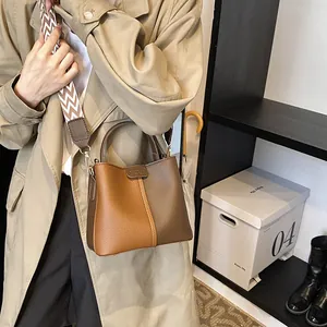 Detail of two-tone bucket bag with lychee texture and striped canvas shoulder strap
