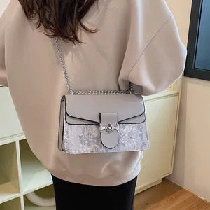 Side view of a light gray crossbody bag with floral print and silver chain strap