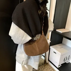 Détail du sac demi-lune en daim café avec coutures verticales et bandoulière en cuir