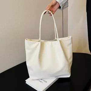 Detail view of large cream pleated tote bag showing soft matte leather texture and handles