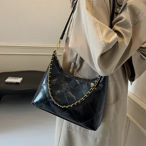 Close-up of quilted black leather texture with gold chain detail on the shoulder bag