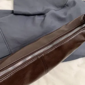 Primer plano de cremallera metálica plateada y costuras en bolso de cuero marrón oscuro