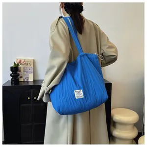 Detailed view of blue pleated nylon tote bag with drawstring closure on female shoulder