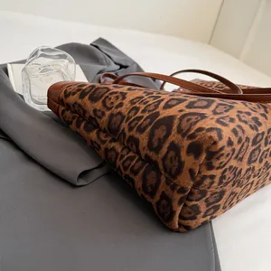 Detail of leopard print tote bag showing matte texture and brown leather bottom stitching