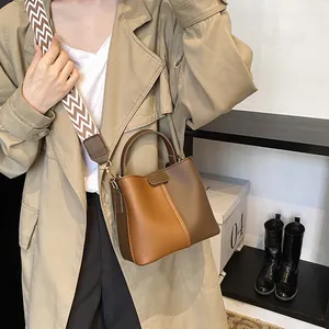 Detail view of brown bucket bag with lychee texture and geometric patterned strap